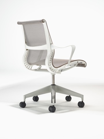 Rear-angle view of a Setu Chair with fixed arms, a studio white frame, silver alloy base and cocoa brown suspension.