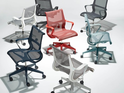 A group of seven Setu Chairs in a circle in the following finishes: nightfall blue, mineral light grey with a white frame, carbon grey, graphite dark grey, glacier light blue, light brown cocoa with a white frame and canyon red.