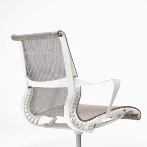 A rear-angle view of a Setu chair with fixed arms, a studio white frame, silver alloy base and cocoa brown suspension.