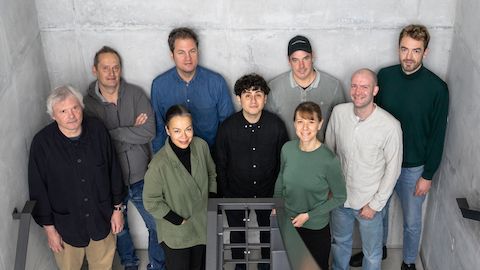 The Studio 7.5 design team standing together in a group in a stairwell.