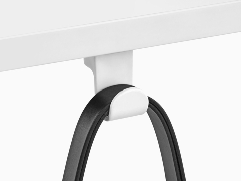 A black strap loops over a fixed Ubi Bag Hook affixed to the underside of a work surface.