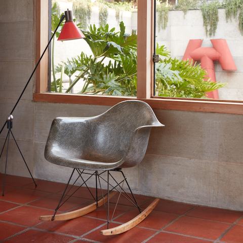 A grey vintage Eames fiberglass armchair on rocker base in the corner of Steve Cabella's living room.