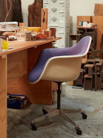 A vintage Eames Upholstered Molded Plastic Armchair in purple in Jesse Schlesinger's studio.