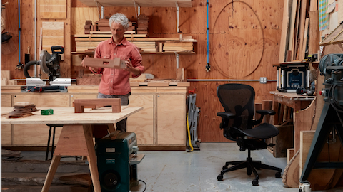 Artist Jesse Schlesinger in his woodworking studio with a black Aeron Chair.