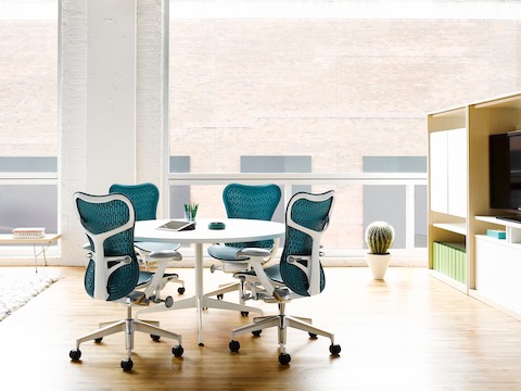 四个蓝色的Mirra 2办公椅围绕着一个白色的Eames桌子，在一个开放的会议区域设有圆顶。