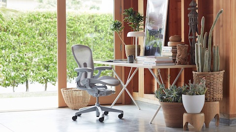 Una sedia Aeron e un tavolo QQX con gambe Nelson in un ufficio a casa. Seleziona per acquistare il negozio Herman Miller e altri rivenditori online.